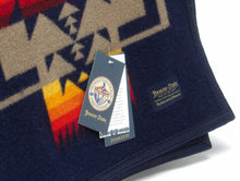 Load image into Gallery viewer, Pendleton Chief Joseph Blanket in indigo featuring a traditional Native American-inspired geometric pattern with arrow motifs, folded neatly to show intricate design and soft wool texture. Tag View