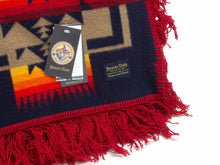 Load image into Gallery viewer, Pendleton Chief Joseph Shawl in indigo, featuring a traditional Native American-inspired geometric pattern with arrow motifs, folded neatly to show intricate design and soft wool texture. Front tag view