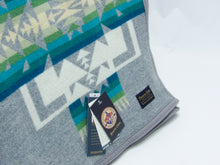 Load image into Gallery viewer, Pendleton Chief Joseph robe in Grey featuring a traditional Native American-inspired geometric pattern with arrow motifs, folded neatly to show intricate design and soft wool texture, tag view