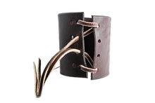 Load image into Gallery viewer, Back view of a leather bow guard which has one long leather tie threaded through 12 holes