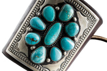 Load image into Gallery viewer, Close up of a dark brown leather bow guard with nine turquoise stones on a silver plate with stamp work on a white background