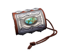 Load image into Gallery viewer, A richly detailed leather bowguard with a rectangular sterling silver plate showcasing flowing stamped patterns and a striking green-blue Sonoran Gold turquoise stone at the center. Decorated with dome-shaped silver conchos and secured with a dark brown leather tie.
