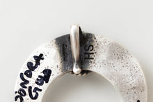 Load image into Gallery viewer, Closeup of Herman Smith hallmark "HS" and the words "sterling" stamped on the back of a silver pendant