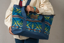 Load image into Gallery viewer, Person holding a blue and green patterned Pendleton tote bag with the Pendleton tag prominent