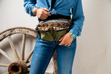 Load image into Gallery viewer, Person wearing a Pendleton patterned waist bag with a rustic wheel in the background