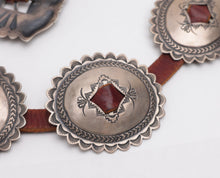 Load image into Gallery viewer, Close-up of a conch belt with stamped silver conchos on a white background