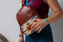 Load image into Gallery viewer, Person holding a Pendleton brown leather bag with a colorful pattern in front of their body, wearing a turquoise bracelet