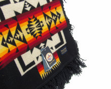 Load image into Gallery viewer, Pendleton Chief Joseph Blanket in Black featuring a traditional Native American-inspired geometric pattern with arrow motifs, folded neatly to show intricate design and soft wool texture. tag view