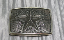 Load image into Gallery viewer, Silver belt buckle featuring a raised five-point star in the center, surrounded by radiating lines in a textured background.