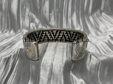 Load image into Gallery viewer, Displays the inside of the bracelet features a geometric zigzag pattern, resembling a traditional or tribal design, engraved into the metal. The pattern alternates sharply, creating a bold visual contrast against the smooth outer surface.