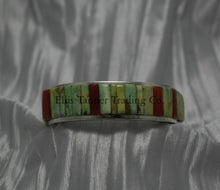 Load image into Gallery viewer, A silver bracelet featuring an intricate cobblestone inlay design with vibrant Carico Lake turquoise and coral stones. The piece is displayed on a soft, textured silver-gray fabric.