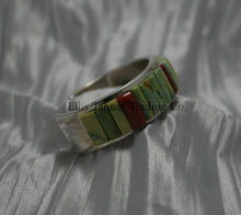 Load image into Gallery viewer, A silver bracelet featuring an intricate cobblestone inlay design with vibrant Carico Lake turquoise and coral stones. The piece is displayed on a soft, textured silver-gray fabric, side profile