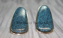 Load image into Gallery viewer, Silver slab-style clip-on earrings featuring polished #8 turquoise stones with a speckled pattern, set in sterling silver bezels, displayed on a black card against a textured silver background.