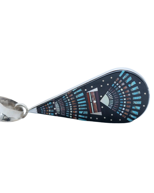 Teardrop-shaped pendant with decorative night Sky pattern, placed in a silver plate and silver bail at the top, laying sideways on a white background
