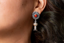 Load image into Gallery viewer, Close-up of a silver earring with a red gemstone worn by a person.
