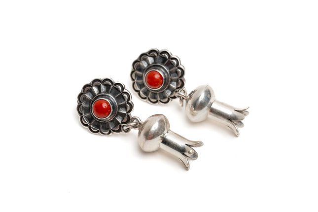 Pair of silver earrings with a single coral stone in the center of silver shaped like a blossom on a white background