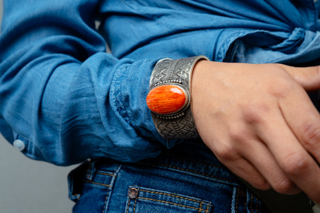 Woman's hand wearing a silver bracelet with an orange gemstone