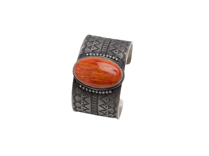 Cuff bracelet featuring a large spinner oyster stone in the center and silver stamped design on a white background