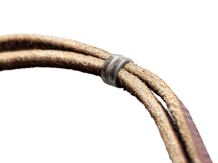 Close-up of a brown leather cord with a metal ring on a white background