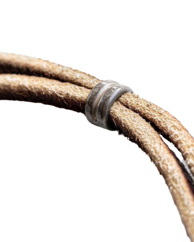 Close-up of a brown leather cord with a metal ring on a white background