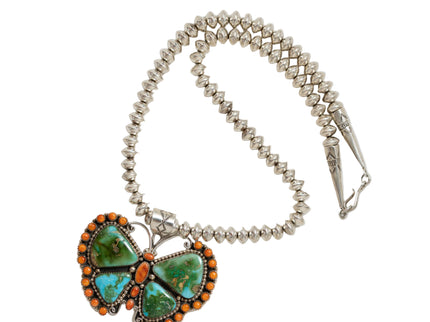 Butterfly-shaped pendant with turquoise and orange stones on a beaded necklace against a white background