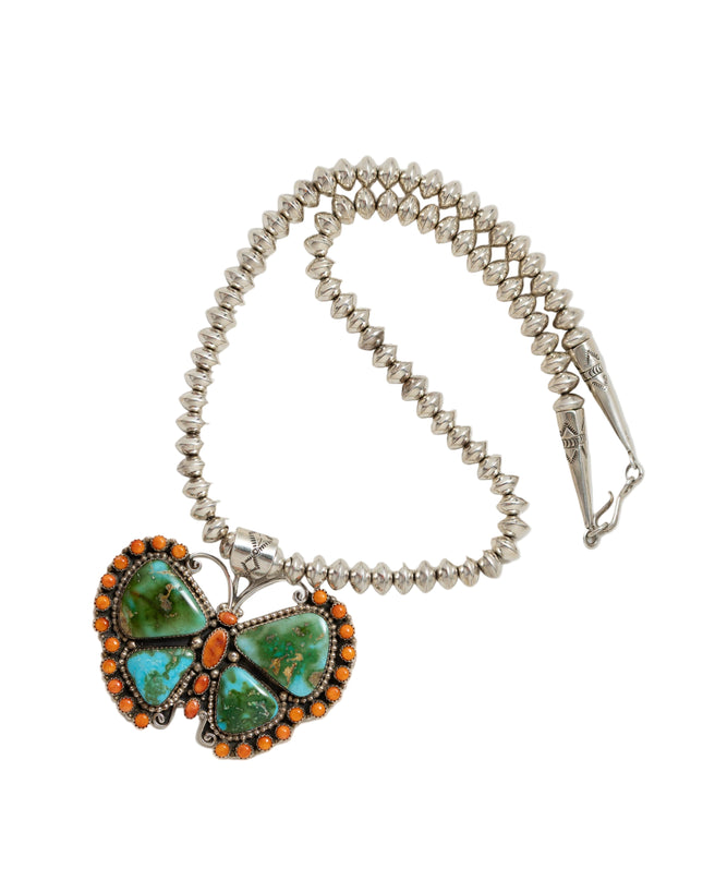 Butterfly-shaped pendant with turquoise and orange stones on a beaded necklace against a white background