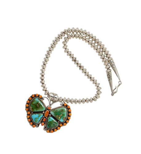 Butterfly-shaped pendant with turquoise and orange stones on a beaded necklace against a white background