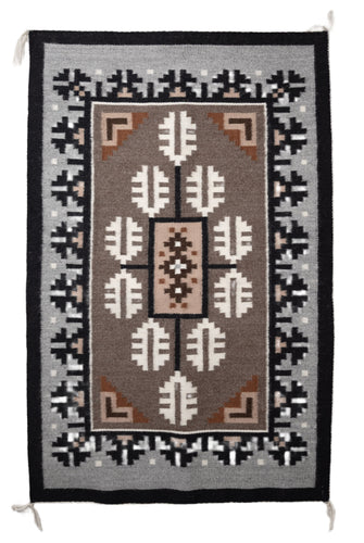 Traditional Navajo handwoven rug with a brown center and a grey and black borden featuring a Navajo geometric patterns