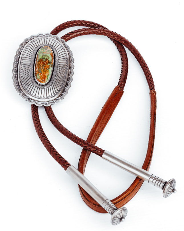 A Sterling Silver Bolo Tie with a Brown Leather Strap, featuring a central emerald-colored stone and two silver tips.