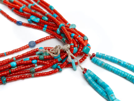 Close up view of a single Native American necklace with nine strands of Mediterranean coral with sleeping beauty, Royston and Kingman Turquoise stones, and Lapis on a white background