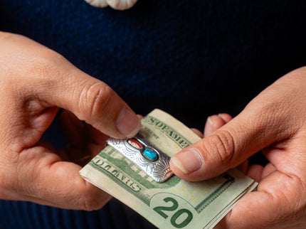 Close-up of hands holding a twenty-dollar bill with a Native American silver money clip