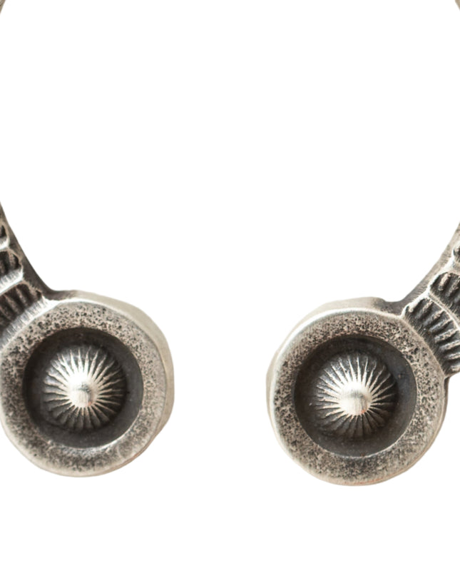 Closeup of Silver u-shpaed pendant tips intricate stamped designs on a light background