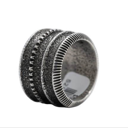 Silver ring with textured design on a white background