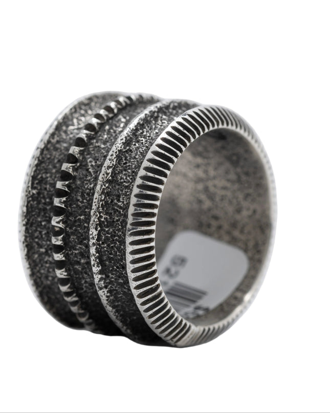 Silver ring with textured design on a white background