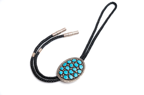 Black leather bolo tie with large circular silver with 17 turquoise stones on a white background