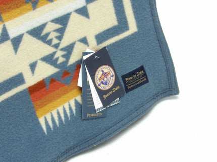 Pendleton Chief Joseph Blanket in Shale featuring a traditional Native American-inspired geometric pattern with arrow motifs, folded neatly to show intricate design and soft wool texture., tag view
