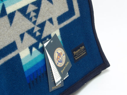 Pendleton Chief Joseph Blanket in Aegean featuring a traditional Native American-inspired geometric pattern with arrow motifs, folded neatly to show intricate design and soft wool texture. Tag View