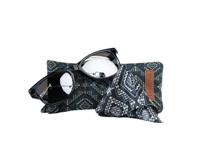 Pendleton dark grey sunglasses lay on a Pendleton patterned dark teal sunglasses case with a brown leather Pendleton label on a white background