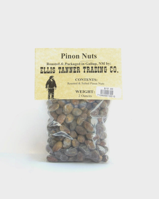 A clear plastic package containing roasted pinon nuts, with a label displaying the brand name, product name, and weight.