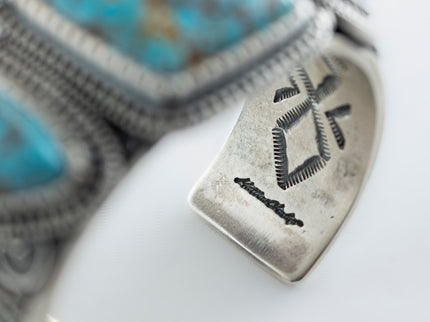 Inside close up of artist hallmark, in cursive writing stamped "Matthew Charley" with a solid white background. 