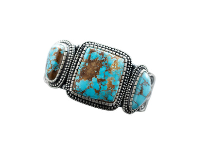 Top of a silver bracelet with three Royston Turquoise stones, by Navajo Silversmith Matthew Charley, with a solid white background. 