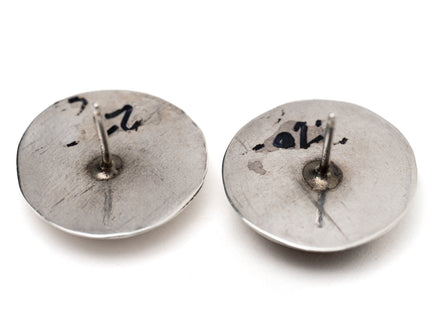 Back of a pair of studded silver earrings on a white background