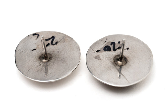 Back of a pair of studded silver earrings on a white background
