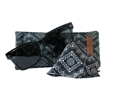 Black sunglasses on leaning on patterned Pendletong  pouch and lens wipe against a white background