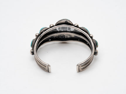 Back view of a Native American silver and turquoise bracelet on a white background