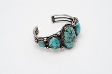 Load image into Gallery viewer, Left side view of a Native American bracelet bracelet with one large turquoise stone in the center with 2 more smaller turquoise stones on each side on a white background
