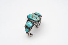 Load image into Gallery viewer, Right top view of a Native American bracelet bracelet with one large turquoise stone in the center with 2 more smaller turquoise stones on each side on a white background
