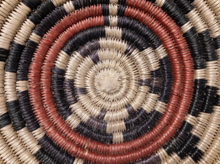 Close-up of a woven basket with concentric circle pattern in earthy tones.
