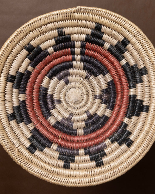 Vintage hand-woven basket with concentric circle pattern on a brown background