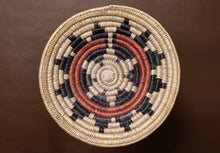 Load image into Gallery viewer, Vintage hand-woven basket with concentric circle pattern on a brown background
